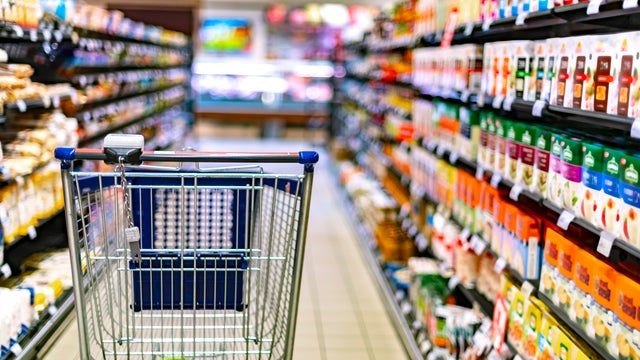 A shopping cart by a store shelf in a supermarket 