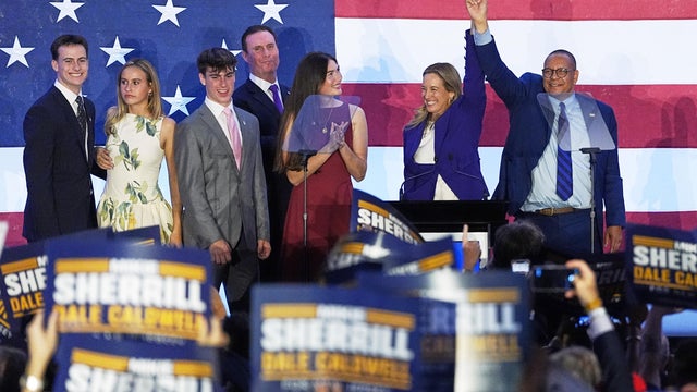 Mikie Sherrill and Dale Caldwell with their families on stage in front of supporters on Election Night 