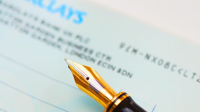 Close up of an ink pen and a cheque book. 
