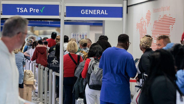 Travelers wait in line at a TSA checkpoint at Dallas-Fort Worth International Airport in Dallas, Texas, on Monday, Oct. 20, 2025. 