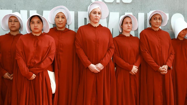 Performers dressed in Handmaid costumes 