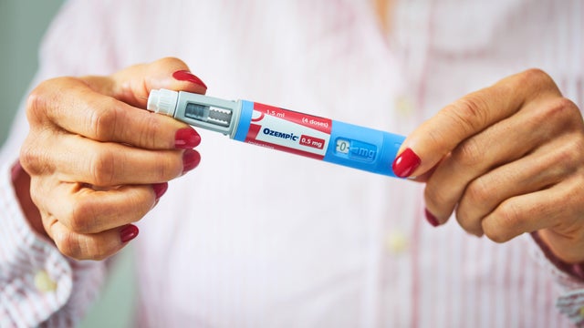 A photo illustration of woman holding a Ozempic pen. 