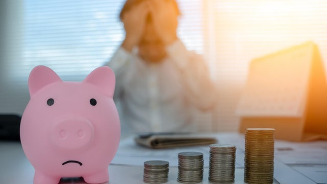 Piggy bank sad with pile coins focus. blur man stressed with Debt and expenses problems, no money to pay, checks, credit card, Broke, mortgage, loan, bankruptcy 