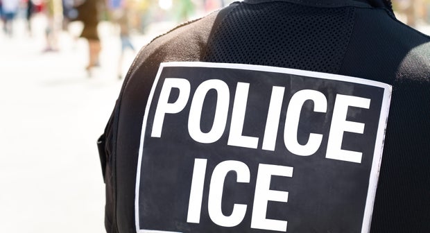 Ice Police Immigration and Customs Enforcement - Close-up of POLICE ICE marking on the back of a hi-visibility stab proof vest worn by a police officer at the scene of an incident.
