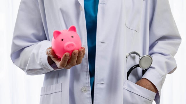 Doctor holding piggy bank in financial insurance concept in hospital 