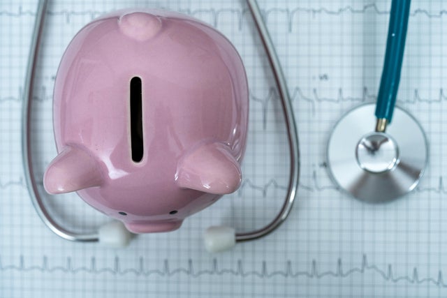 Piggy bank with stethoscope on illustration of wave form on checked ecg graph background, health saving account, insurance, top view 