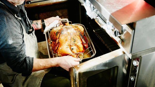 Man pulling cooked turkey out of oven 