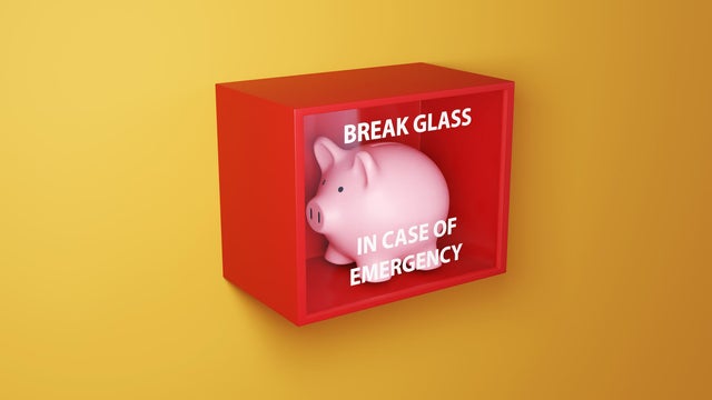 Pink piggy bank in a red box with a glass printed with the instruction BREAK GLASS IN CASE OF EMERGENCY on a yellow wall. Illustration of the concept of emergency fund and financial buffer 