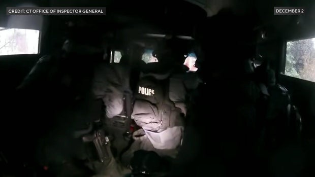 Police officers wearing helmets and bulletproof vests inside an armored vehicle