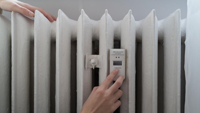 Young woman near the home radiator with temperature sensor 