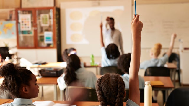 Girl raising hand and answering in classroom 