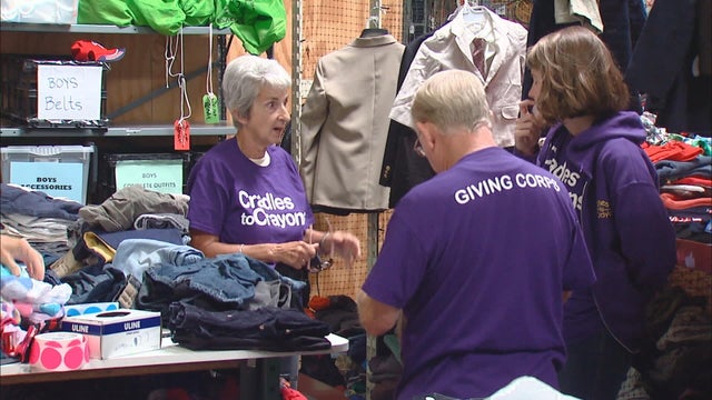 A boy wearing a winter coat and hat Clears Snow From a Car 