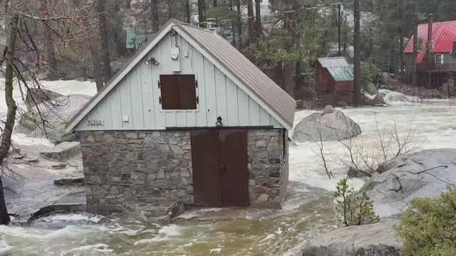 A rain-swelled Yuba river is seen partially flooding an outside structure 