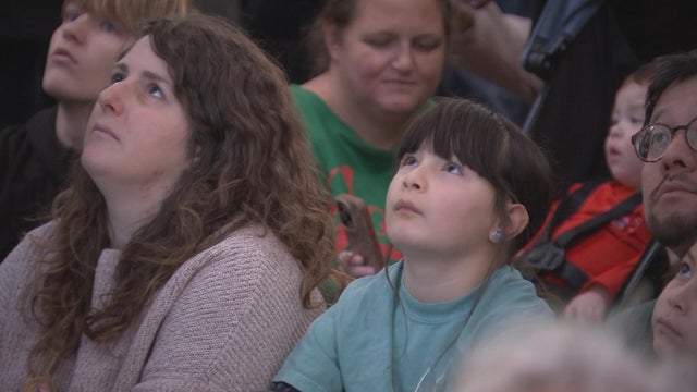 People look up to see the Wanamaker Building's holiday light show in Philly 