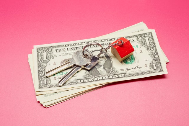 High angle view of keyring with a small house and American Dollar banknotes on colored background 