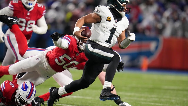 Philadelphia Eagles' Jalen Hurts, right, scrambles past Buffalo Bills' Greg Rousseau during the first half of an NFL game in Buffalo 