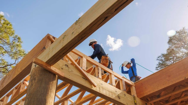 Low angle view of male carpenters working on rooftop of construction frame 