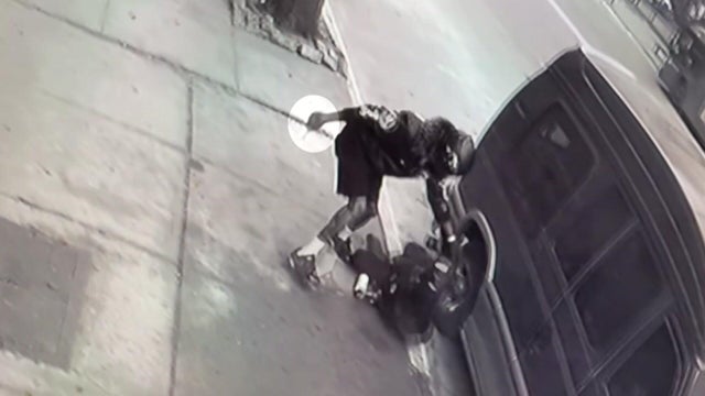 A man about to stab another man on the ground on a sidewalk 