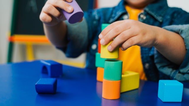 Kid hands playing with wood toys at preschool for development therapy. School, kindergarten education for children 