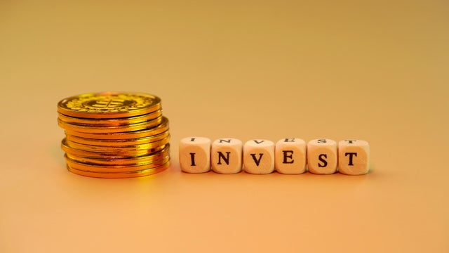 invest word with gold coins stack 