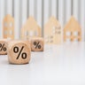 wooden cubes with percent signs in front of wooden houses 