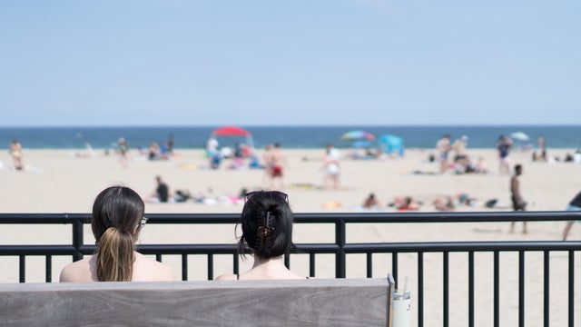 Two young women sit on a bench overlooking Hampton Beach, NH. 