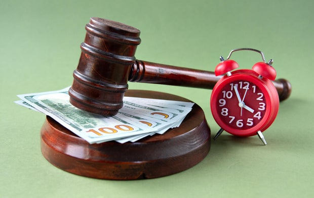 The judge's gavel lies on the counter against the background of banknotes and an alarm clock 