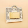 High angle view of a bunch of American Dollar banknotes and closed padlock on beige background 