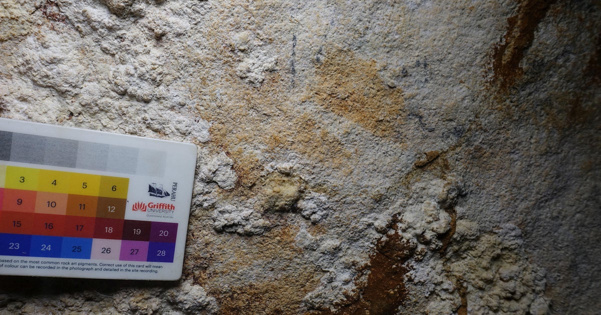 Червен шаблон на ръка притисната към стената на индонезийска пещера