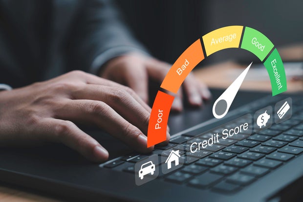 Close-up of hand typing on a laptop with a credit score gauge displayed. The gauge indicates varying levels of credit quality from poor to excellent for highlighting the importance of financial health