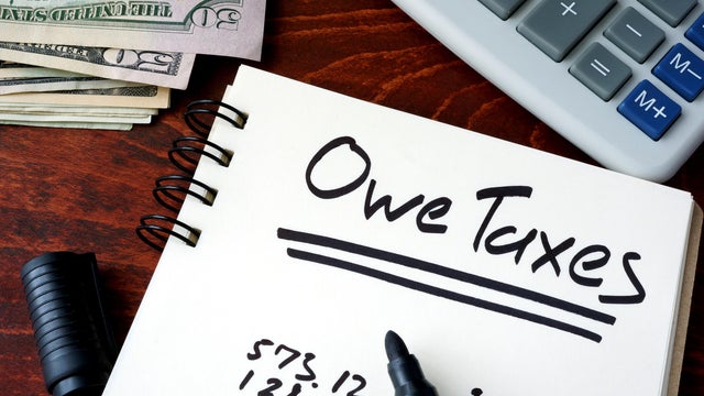 Notepad with sign Owe Taxes on a wooden background. 
