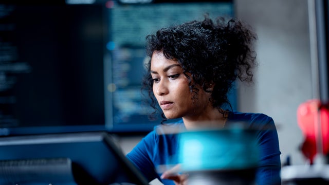 Improve Automate Workflows and Streamline Software Testing with Machine Learning in Software Development. An Asian female software developer coding or debugging code on a computer at her desk in the tech office. 