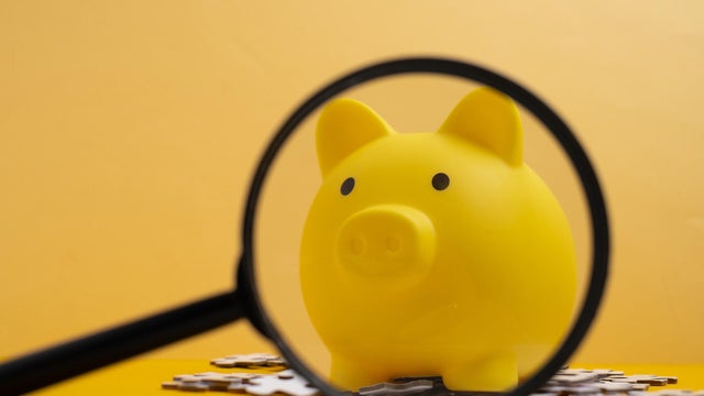 Yellow piggy bank with magnifying glass and puzzles. Financial planning and investment strategy concept. 