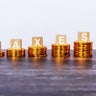 Taxes written on wooden block with stacked coins 