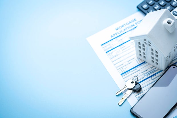 Flat lay of real estate concept. Mortgage application form, house model, house keys and mobile phone with blank screen. Copy space 