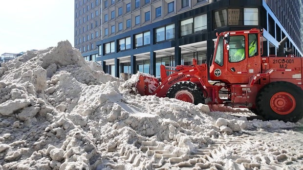 A DSNY front loader approaches a mound of snow