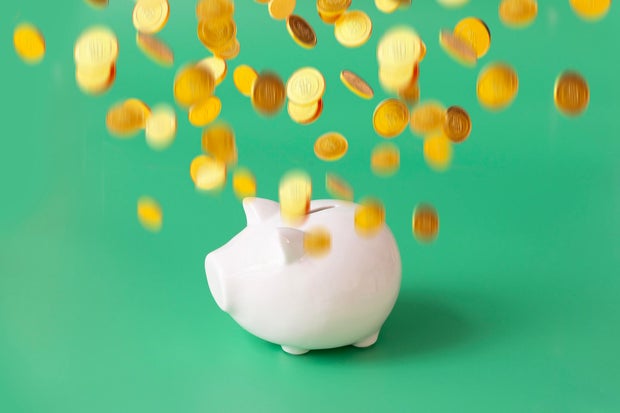 Financial freedom concepts still life - gold coins flying on top of piggy bank.
