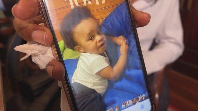 Sharee Collins shows her phone to the camera with a picture of her son Sy'vir Hill 