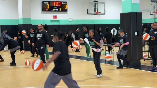 Middle school girls dribbling basketballs on a basketball court