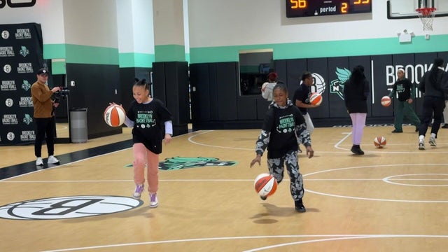 Middle school girls dribbling basketballs on a basketball court