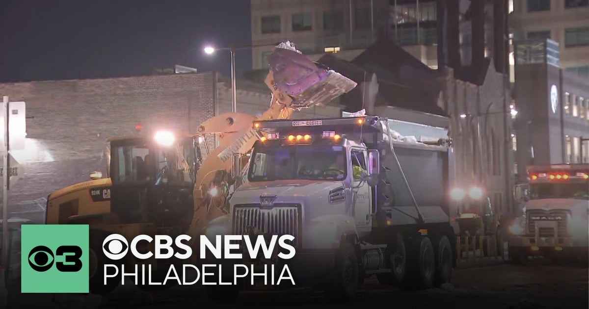 Crews lift snow off Broad Street near Erie Avenue in North Philadelphia