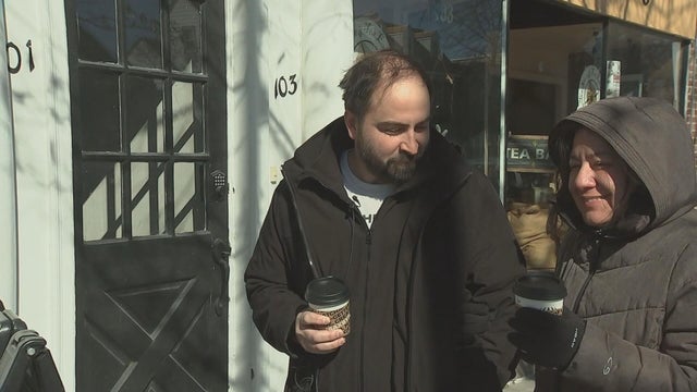 Two people walk outside holding warm drinks 