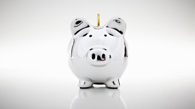 Gold coin dropping into piggy bank 