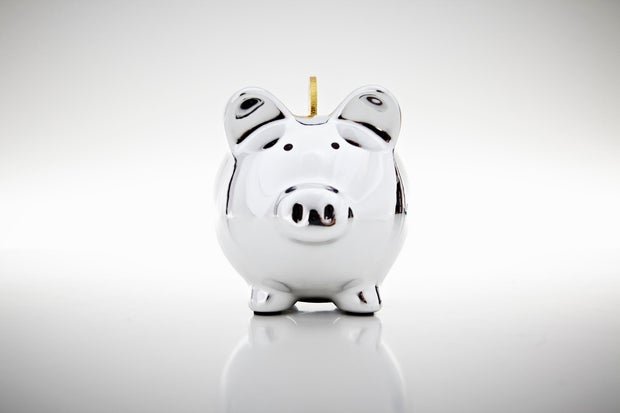 Gold coin dropping into piggy bank 