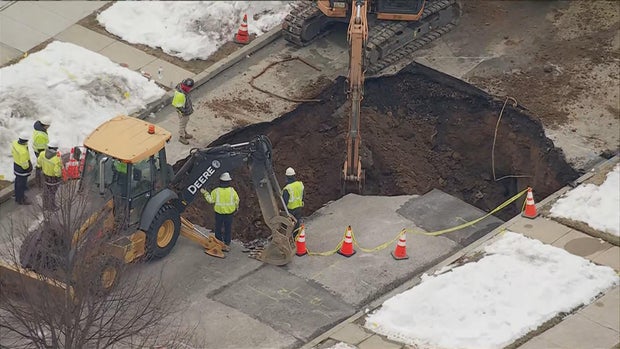 Construction workers and vehicles are on the scene of a sinkhole in the road in Conshohocken