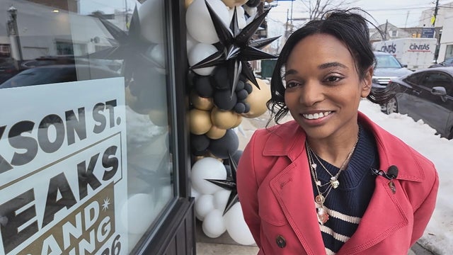 Joi Washington smiles outside a restaurant during its grand opening 