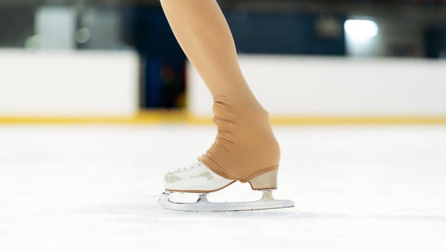 Figure skater's leg with ice skate on rink 
