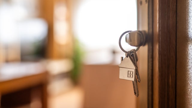 House-shaped keys are hanging from the door knob of a new home, representing the exciting moment of acquiring property and starting a fresh chapter 