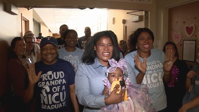 Chi Obidike and baby Myla walk out of the NICU, surrounded by relatives and supporters 