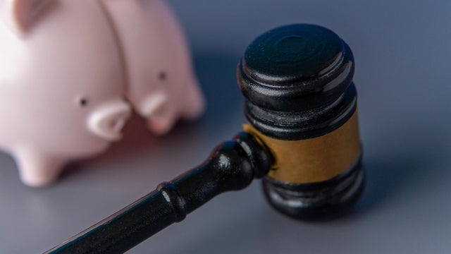 A broken pink piggy bank and a judge's gavel. 
